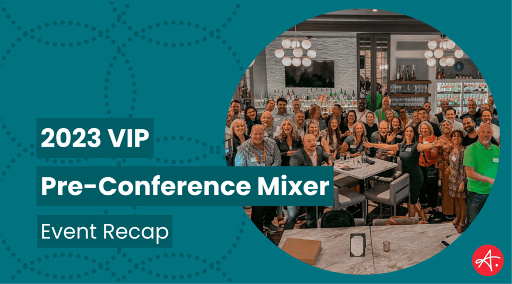 A lively group of conference attendees gathered in a modern bar setting during the 2023 VIP Pre-Conference Mixer. People are smiling, mingling, and posing for a group photo, surrounded by a well-stocked bar and elegant lighting.